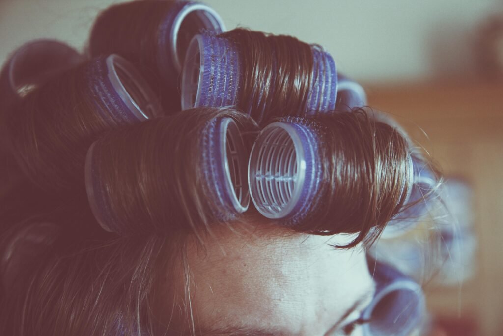 Vintage-style close-up of a woman's hair in curlers, emphasizing retro hair styling.